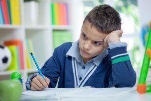 niño agobiado haciendo tareas del colegio porque va mal en los estudios