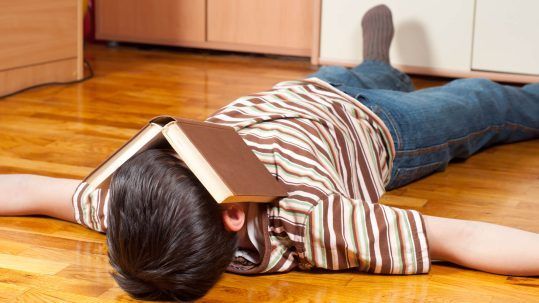Niño con TDAH descansando con un libro tapando su cara