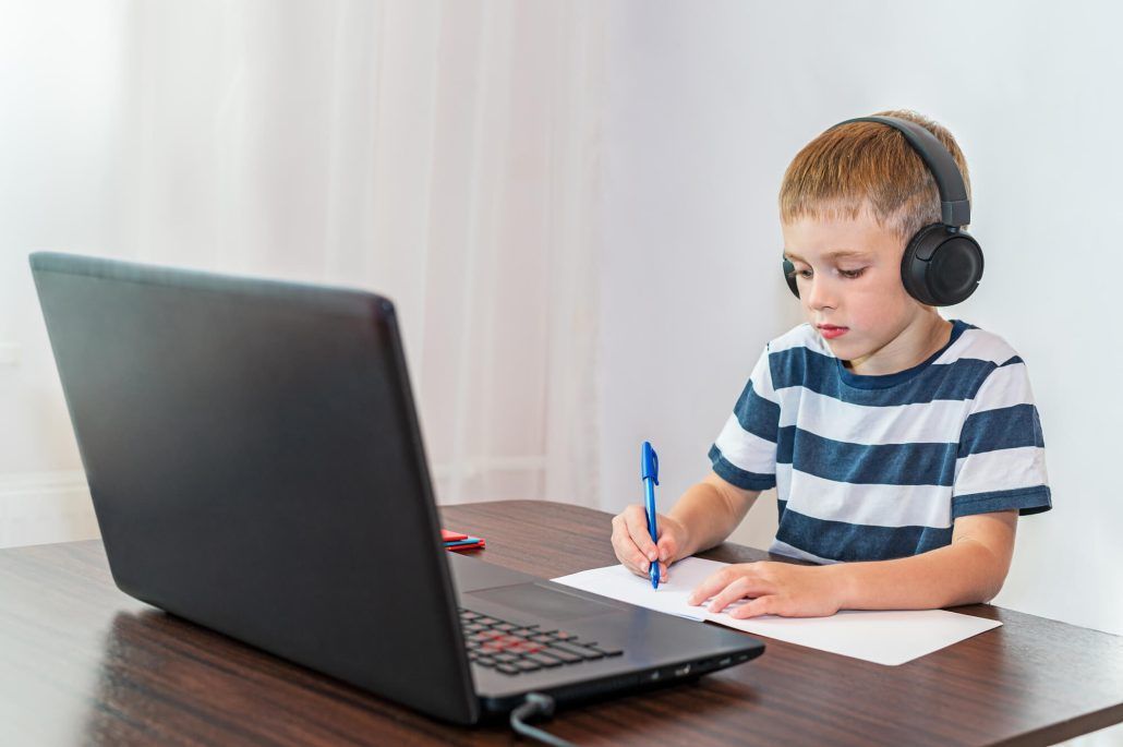 Niño concentrado usando auriculares y trabajando en el ordenador 