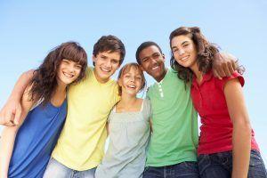 5 adolescentes con buenas habilidades sociales, abrazados posando para una foto