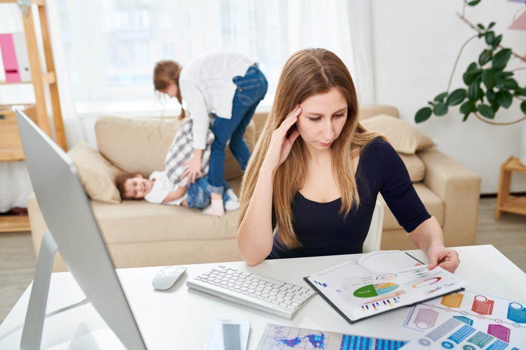 Madre con estilo educativo permisivo trabajando en casa mientras sus hijos saltan en el sofá - Cómo influye en la autoestima en el adolescente